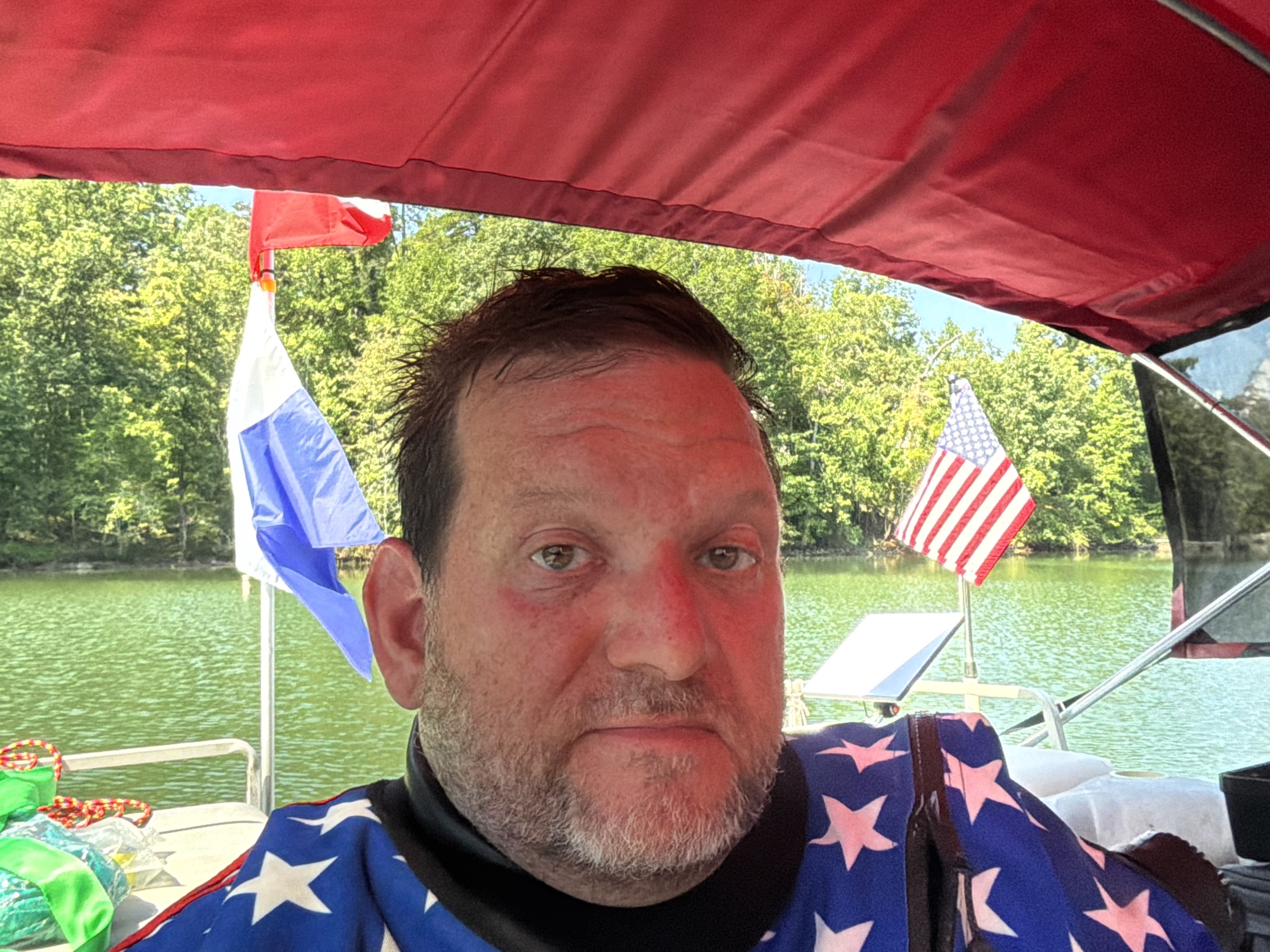 Brent Clevenger on the pontoon at Lake Adger after a dive, with the dive flag, the American flag and the Starlink dish behind him