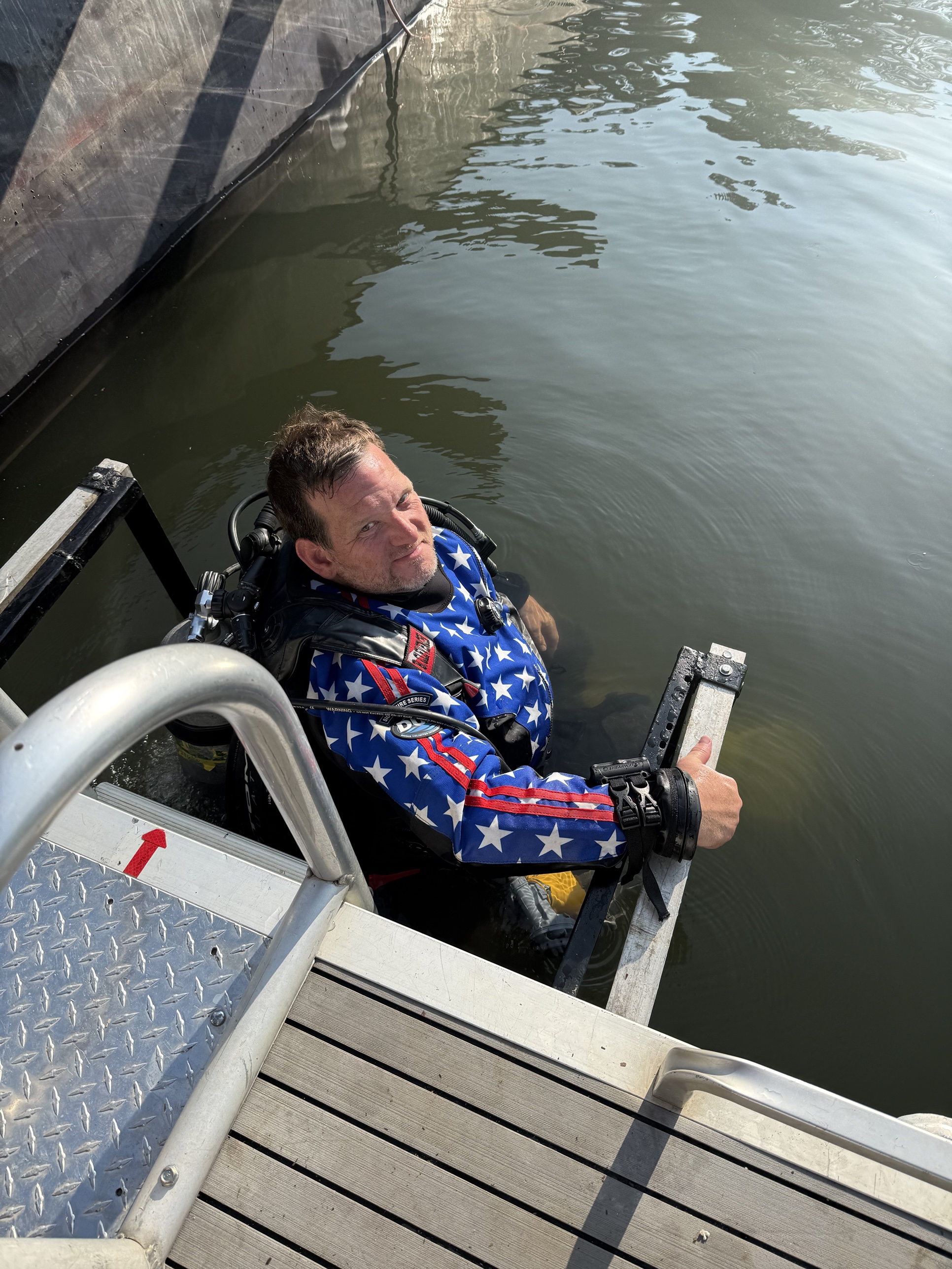 Public safety diver in a DUI drysuit climbing the ladder out of Lake Adger after a debris-rigging dive